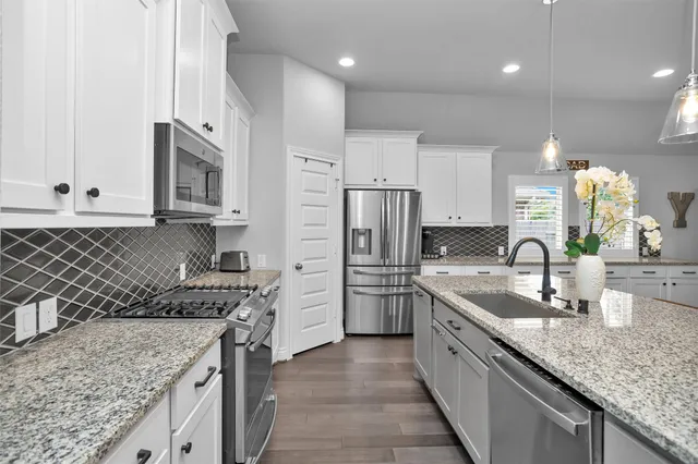 a kitchen with stainless steel appliances granite countertop a sink stove and cabinets