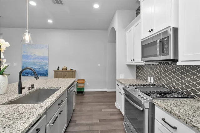 a kitchen with stainless steel appliances granite countertop a table chairs sink refrigerator and microwave