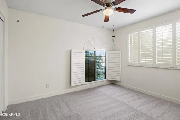 an empty room with windows and fan