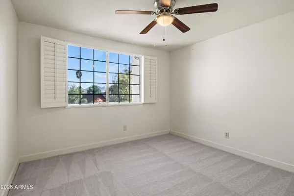 an empty room with a window and a fan