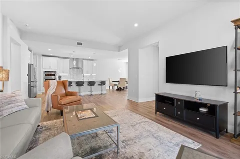 a kitchen with stainless steel appliances granite countertop a stove a sink a refrigerator and a dining table with wooden floor