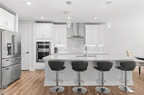 a kitchen with stainless steel appliances granite countertop a stove top oven a sink dishwasher a dining table and chairs with wooden floor