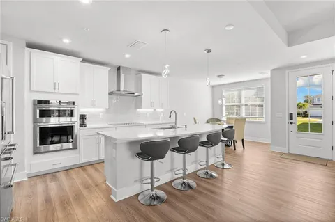 a kitchen with white cabinets a sink dishwasher and a stove with wooden floor