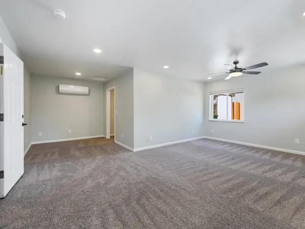 an empty room with ceiling fan and window