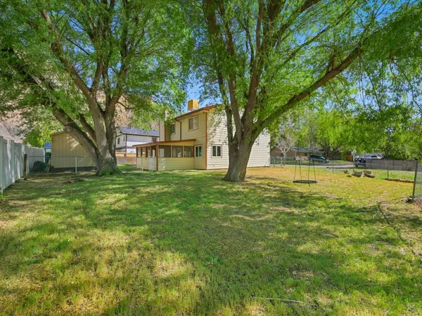 a view of a yard in front of a house with large tree