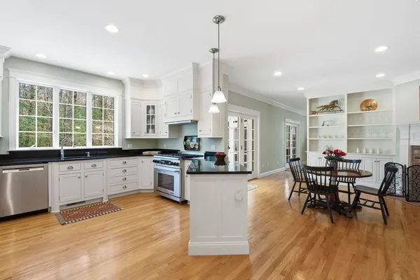 a kitchen with stainless steel appliances granite countertop a table chairs stove and wooden floor