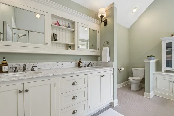 a bathroom with a granite countertop double vanity sink mirror and toilet