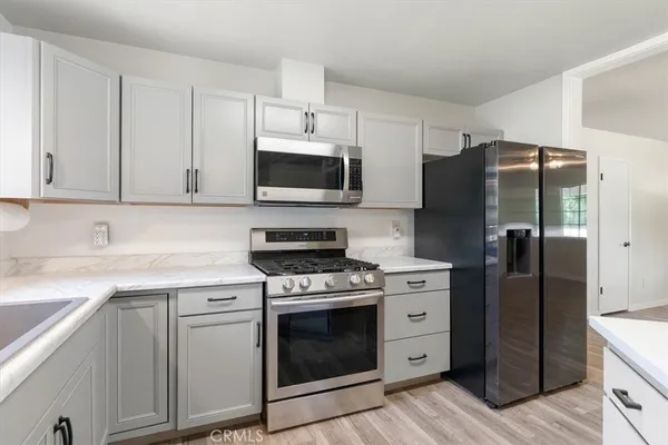 a kitchen with cabinets stainless steel appliances and wooden floor