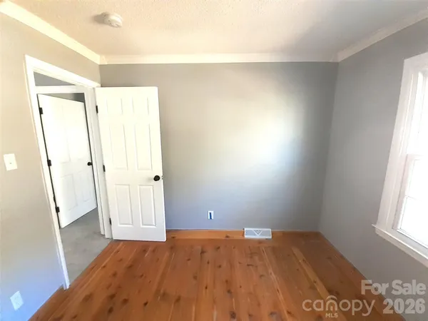 an empty room with wooden floor and window