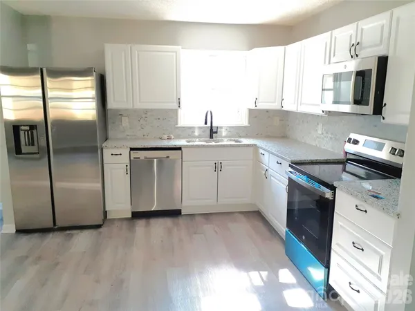 a kitchen with stainless steel appliances granite countertop a sink a stove a microwave a refrigerator a counter space and cabinets