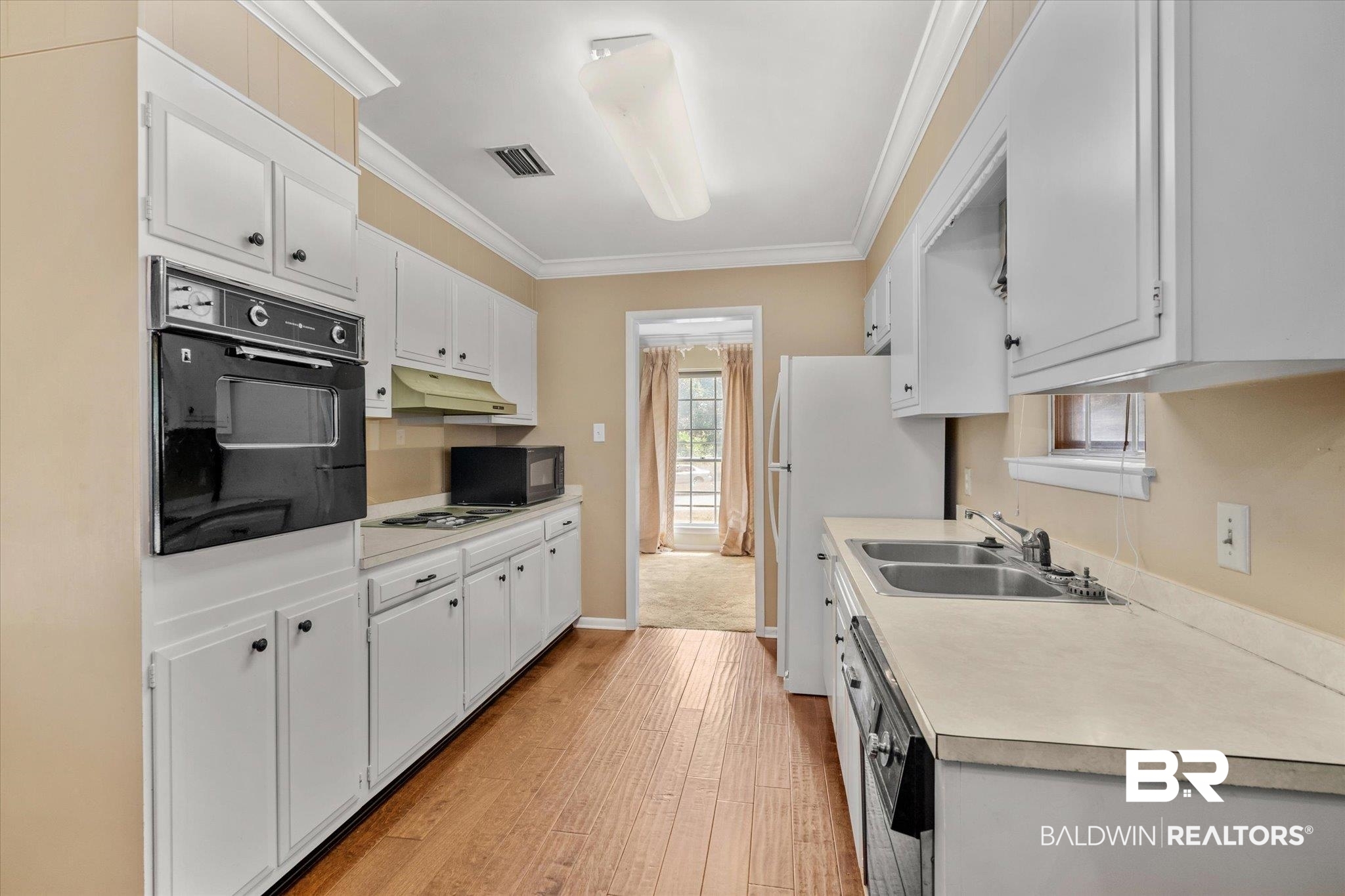 5608 Judson Circle Mobile, AL 36608 - Photo 5 of 20 Kitchen with crown molding, light hardwood / wood-style floors, white cabinetry, sink, and black appliances