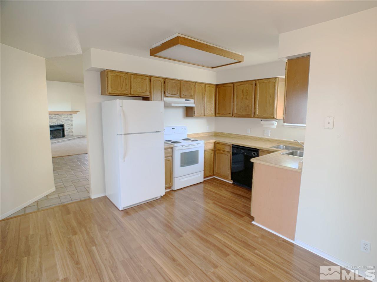 2101 Escalera Way Reno, NV 89523 - Photo 7 of 17 a kitchen with a refrigerator a stove top oven a wooden floor and cabinets
