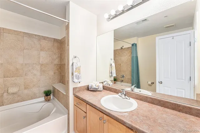 a bathroom with a granite countertop tub sink and mirror