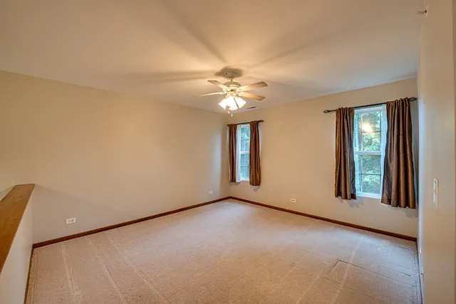 a view of a livingroom with a chandelier fan and windows