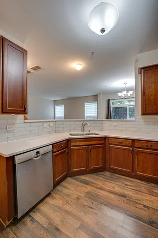 a large kitchen with granite countertop a sink and dishwasher a stove with wooden floor