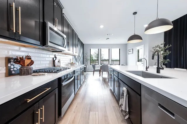 a kitchen with stainless steel appliances granite countertop a sink a stove and a wooden floors