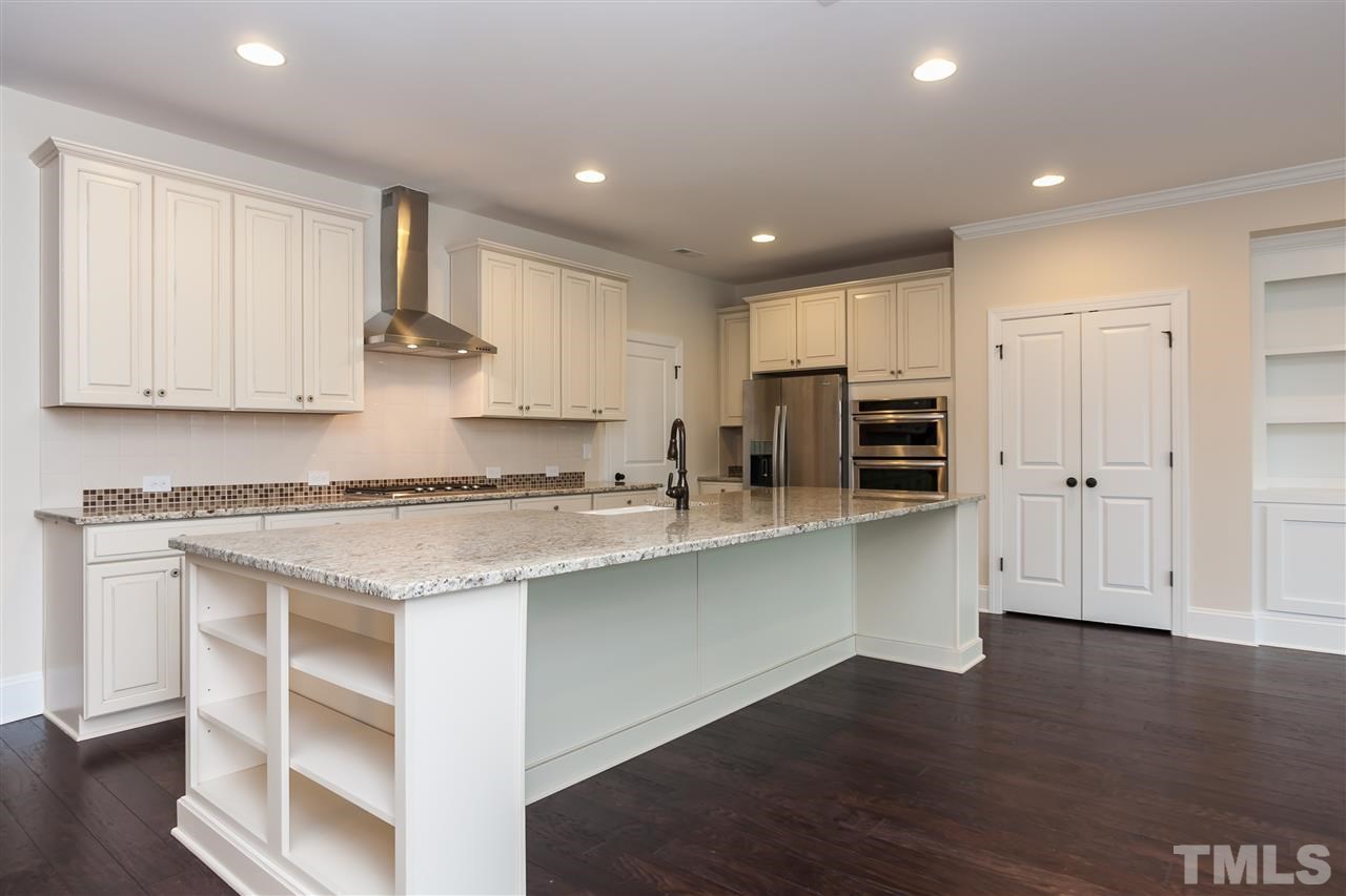 3908 Ivory Rose Lane Raleigh, NC 27612 - Photo 3 of 4 a kitchen with stainless steel appliances granite countertop a stove a refrigerator and white cabinets with wooden floor