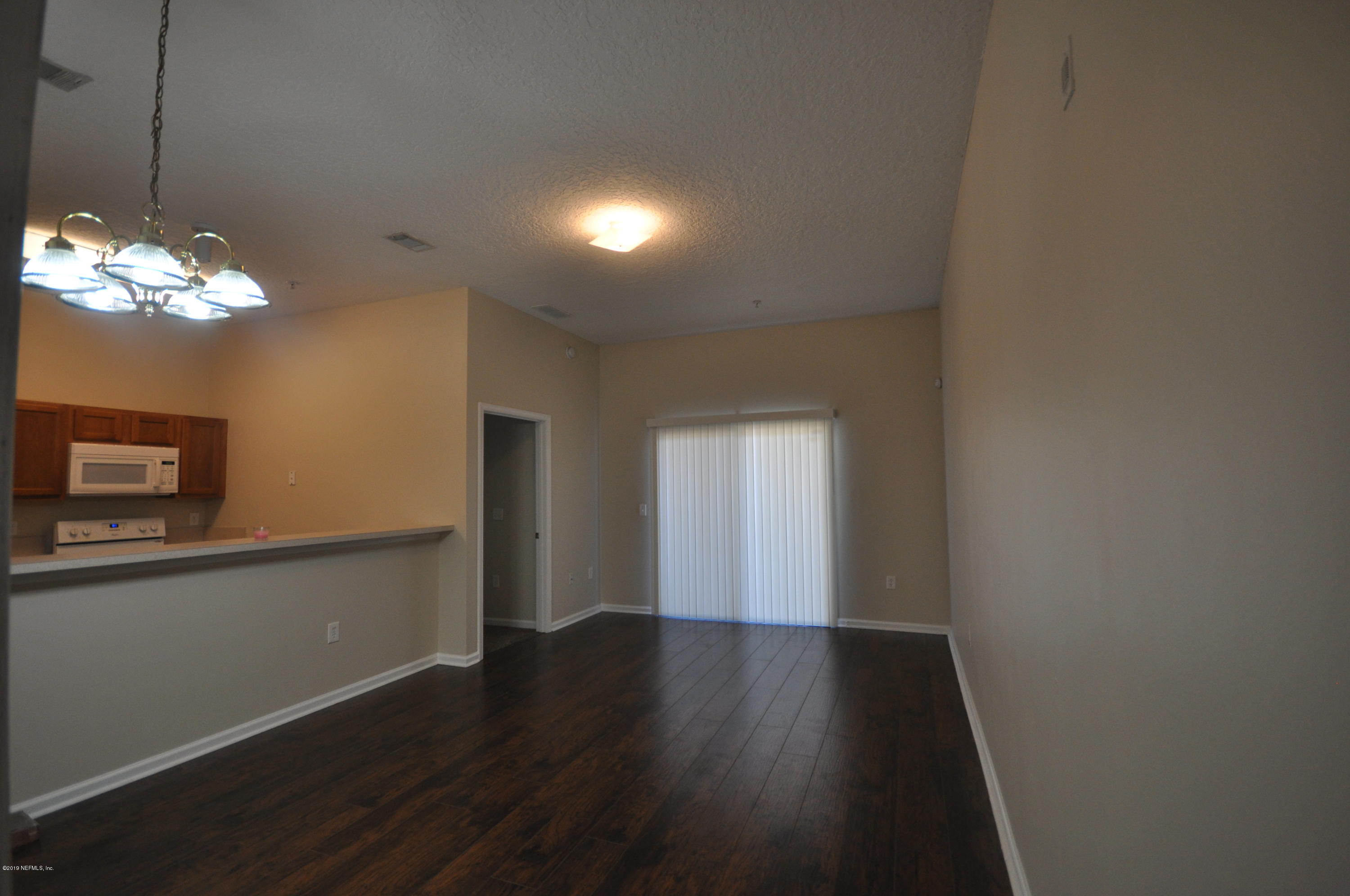 7920 Merrill Road, Unit 1203 Jacksonville, FL 32277 - Photo 2 of 13 a view of a room with wooden floor and chandelier