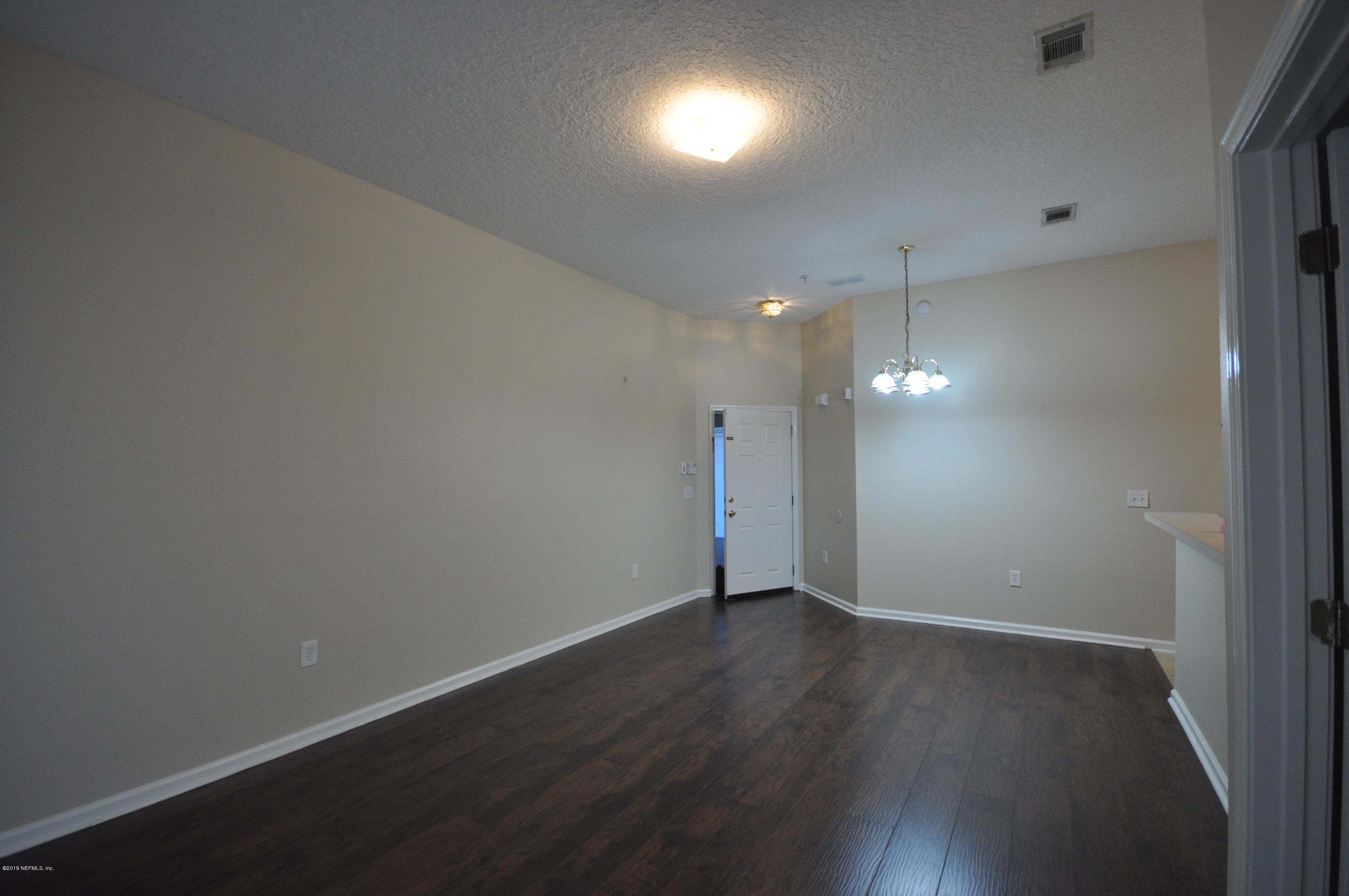 7920 Merrill Road, Unit 1203 Jacksonville, FL 32277 - Photo 4 of 13 an empty room with wooden floor and windows