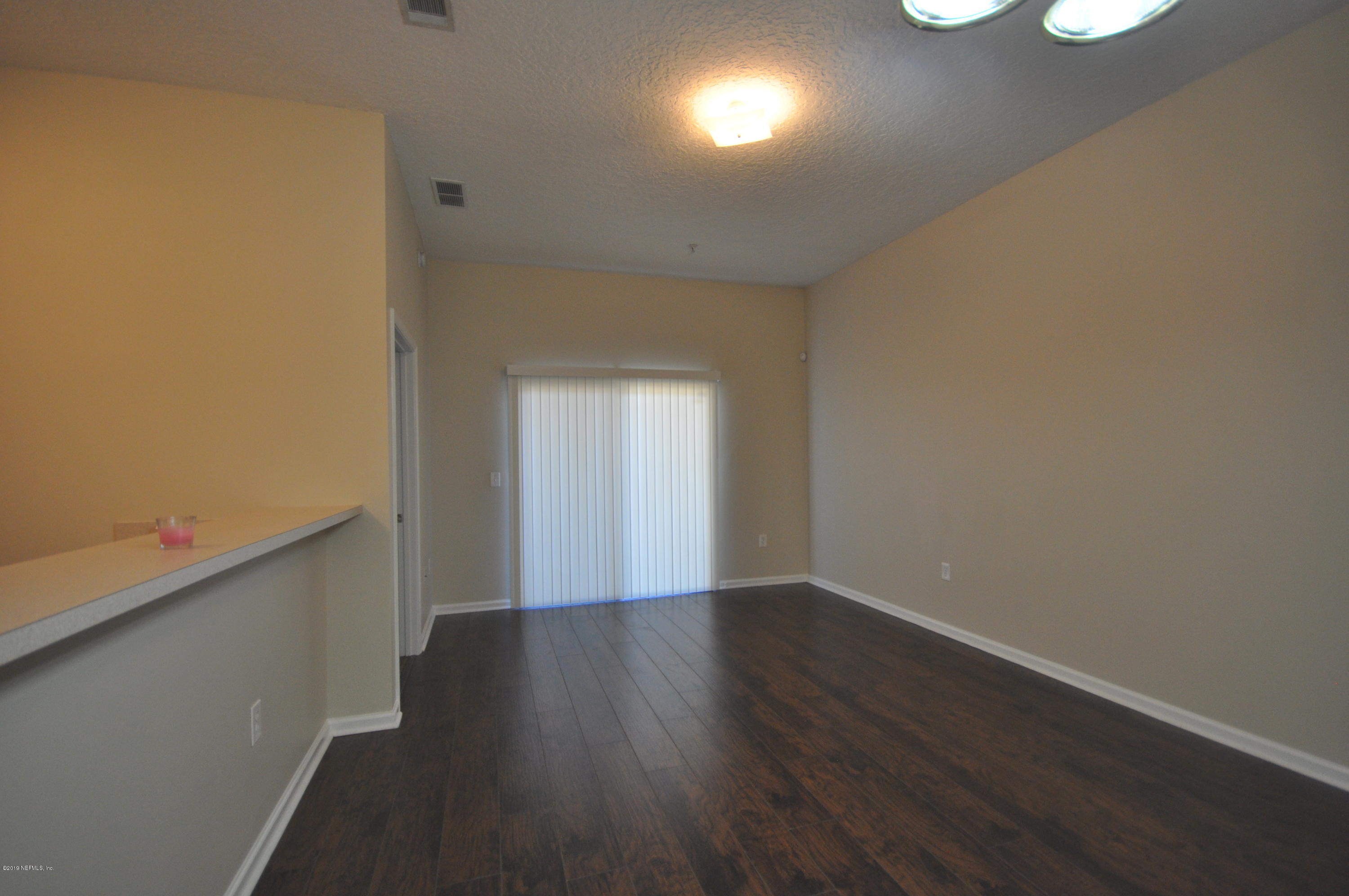 7920 Merrill Road, Unit 1203 Jacksonville, FL 32277 - Photo 5 of 13 a view of an empty room with wooden floor and a window
