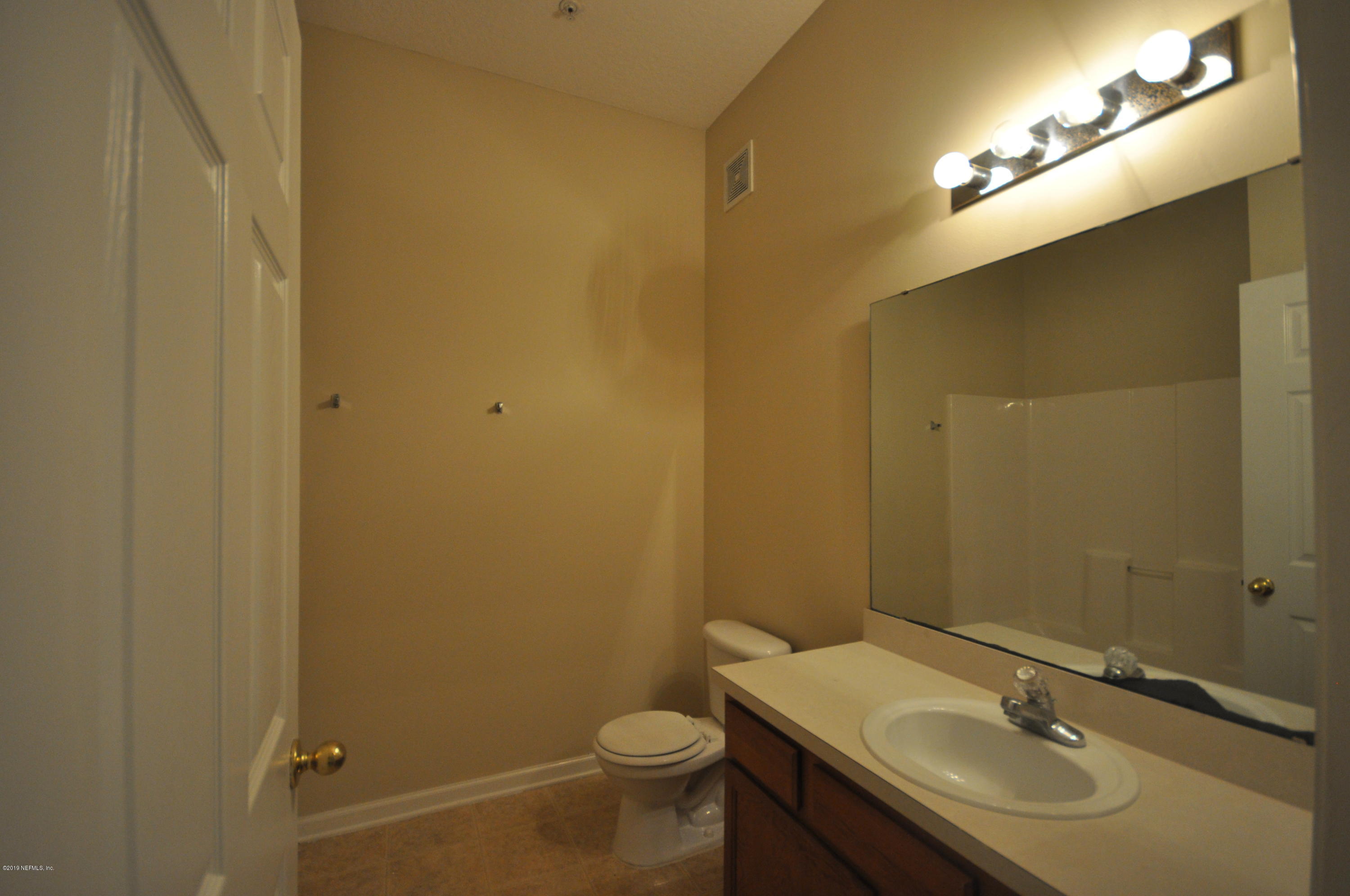 7920 Merrill Road, Unit 1203 Jacksonville, FL 32277 - Photo 8 of 13 a bathroom with a sink and mirror with toilet