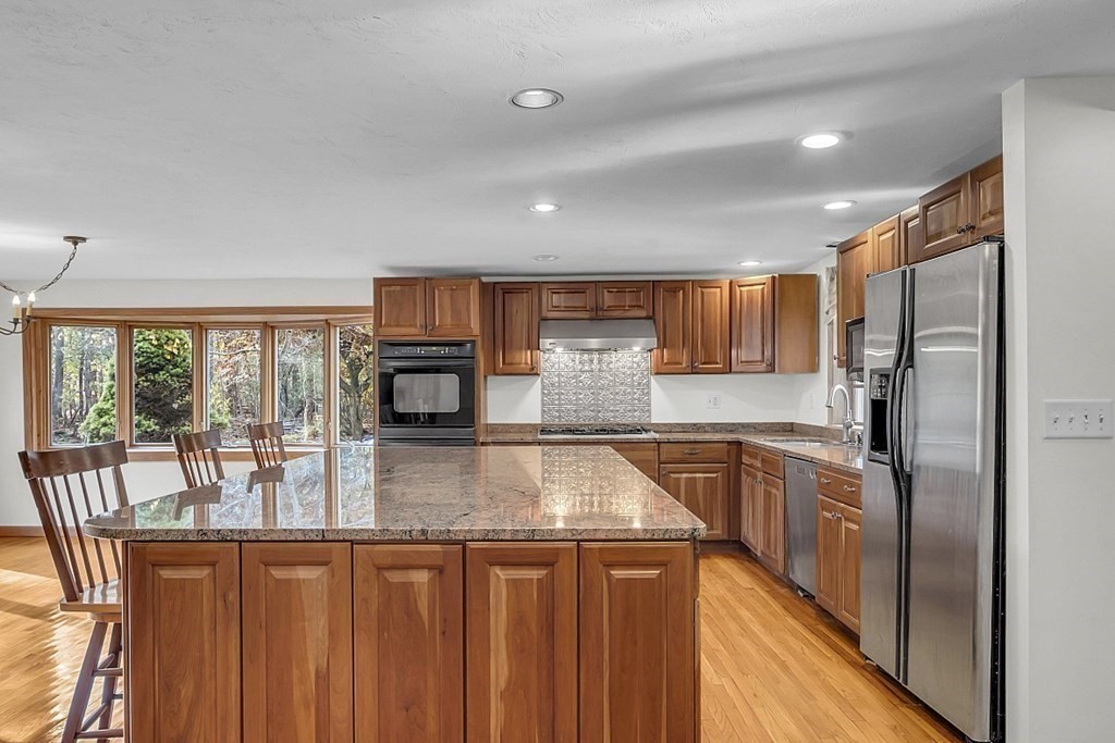 15 Stagecoach Road Topsfield, MA 01983 - Photo 8 of 40 a kitchen with stainless steel appliances granite countertop a refrigerator a stove and a sink with wooden cabinets
