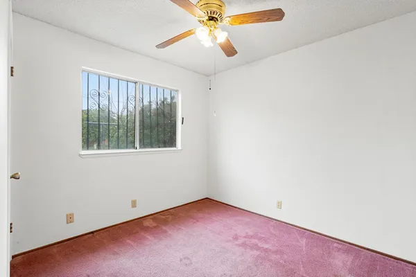an empty room with a window and a ceiling fan