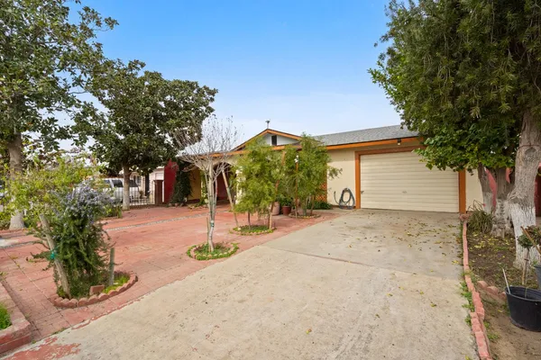 a view of a house with potted plants and large trees