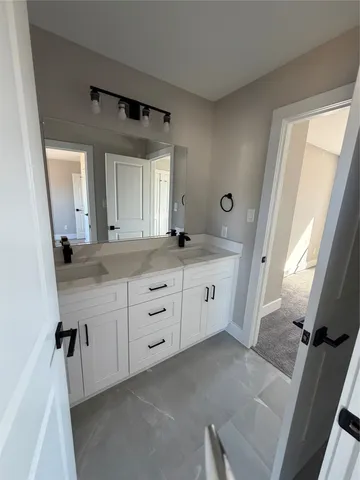 a spacious bathroom with a double vanity sink a mirror a window and a bathtub