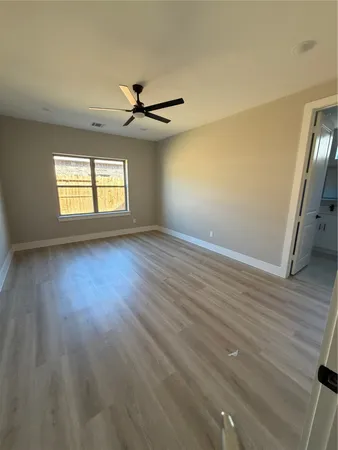 an empty room with wooden floor fan and windows