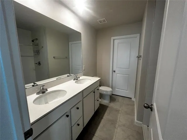 a bathroom with a double vanity sink toilet and shower