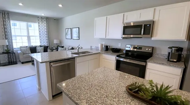 a kitchen with a refrigerator stove microwave and sink