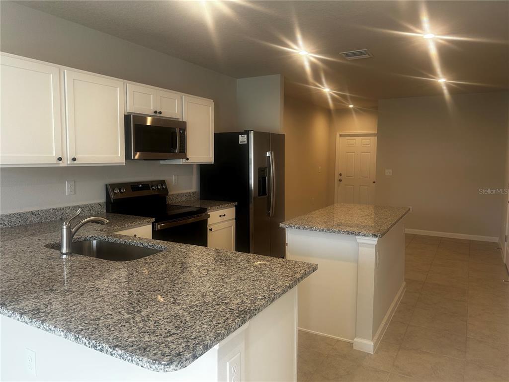 14124 Crimson Avenue Bradenton, FL 34211 - Photo 3 of 27 a kitchen with granite countertop a sink a stove top oven a counter space and stainless steel appliances