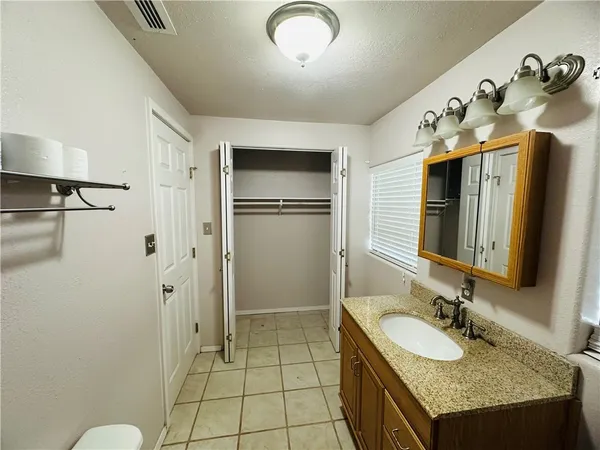 a bathroom with a granite countertop sink a mirror and shower