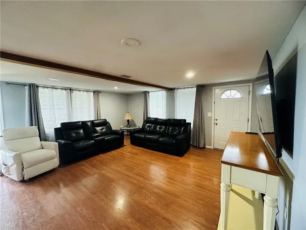 a living room with furniture a flat screen tv and a large window
