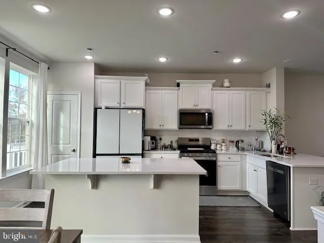 a kitchen with stainless steel appliances granite countertop a refrigerator a stove and a dining table with wooden floor