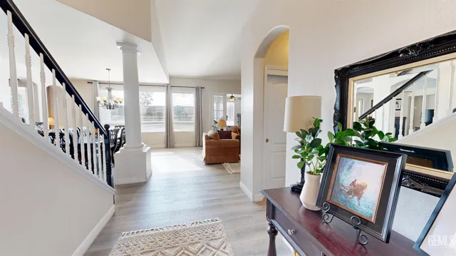 a hallway with wooden floor stairs and a potted plant