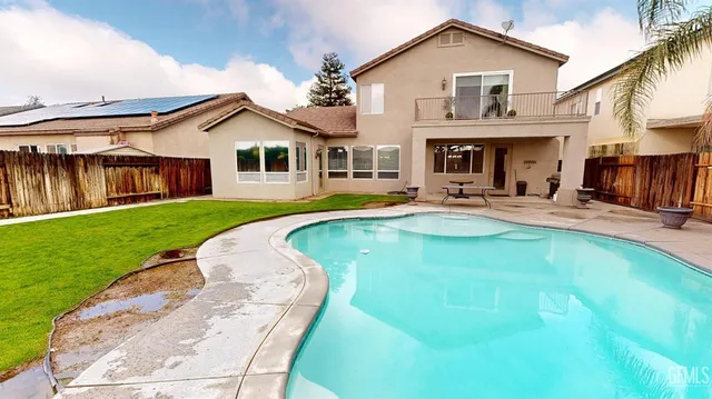 a view of a house with swimming pool lawn chairs and a yard