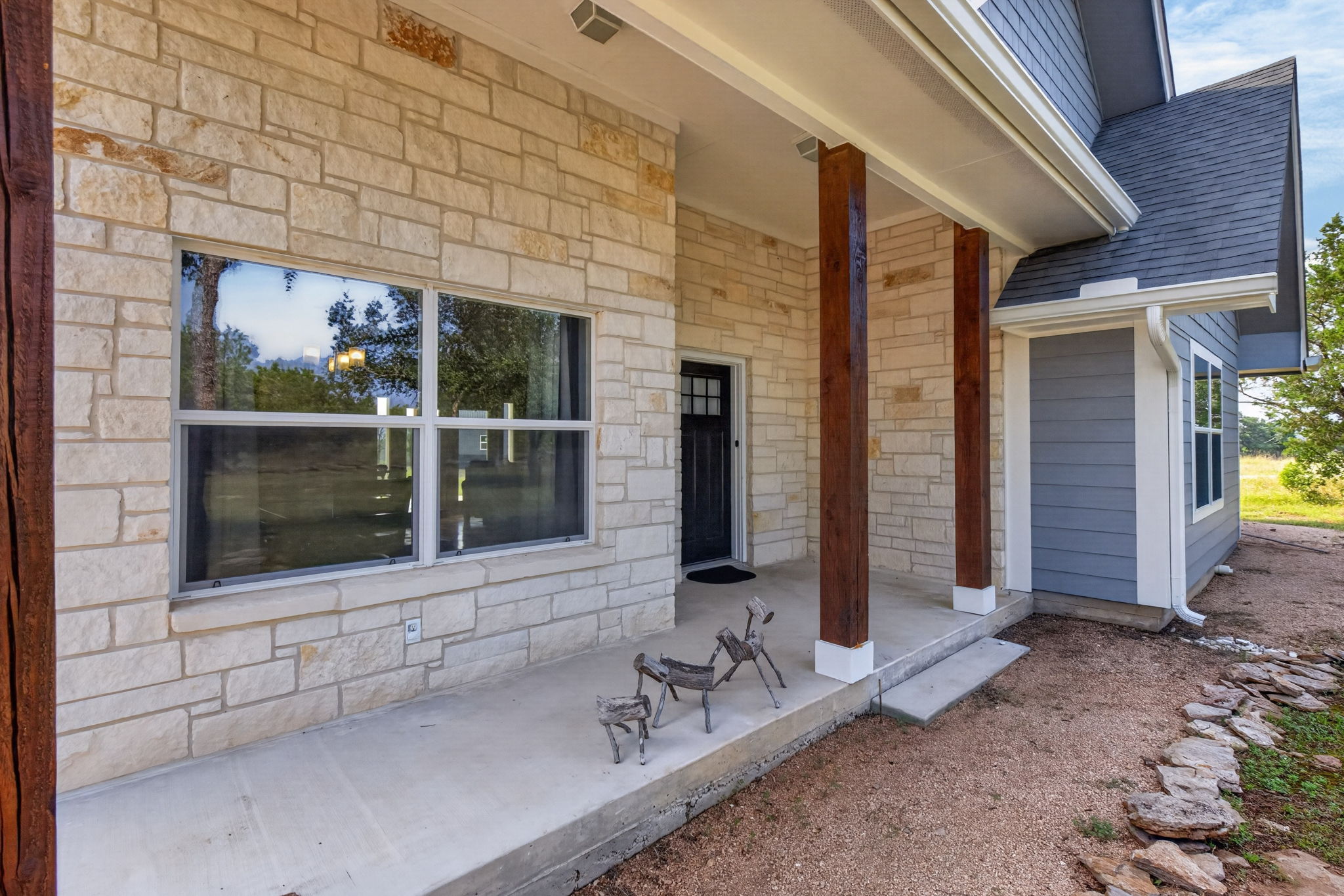 207 Deer Ridge Drive Burnet, TX 78611 - Photo 3 of 36 A welcoming stone facade entrance features sturdy wooden pillars and broad windows, hinting at comfort within.