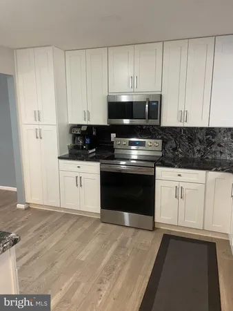 a kitchen with granite countertop white cabinets and stainless steel appliances