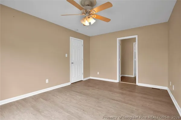 a view of an empty room with window and a ceiling fan