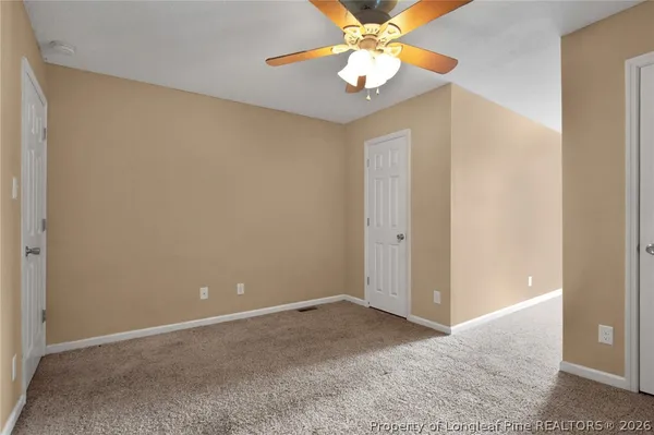 an empty room with a chandelier fan and closet