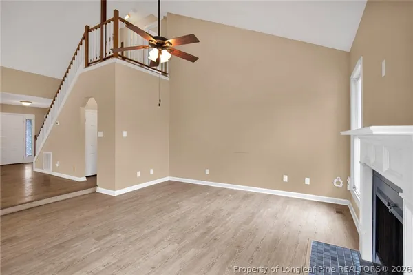 a view of an empty room with wooden floor and a fireplace