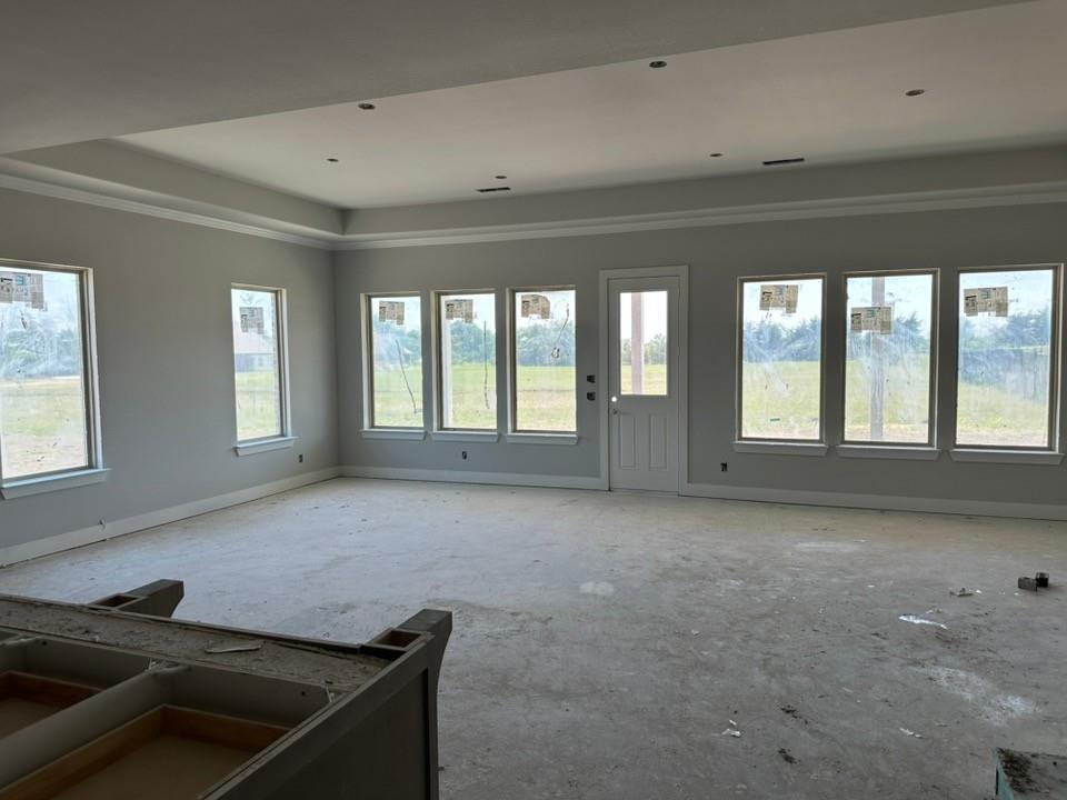 295 Brown Road Leonard, TX 75452 - Photo 9 of 26 Spacious room featuring a tray ceiling with recessed lighting, crown molding, multiple windows, a paneled door with a half-light, and baseboard trim