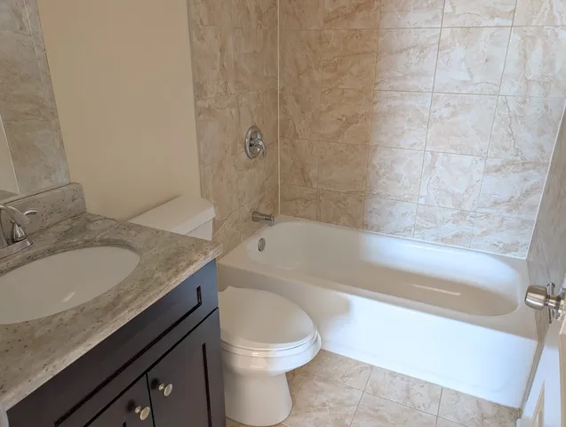 a bathroom with a granite countertop toilet sink and bathtub