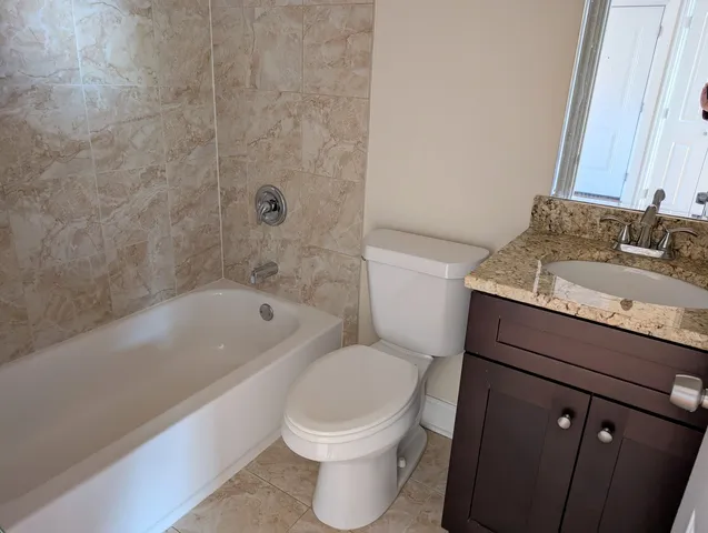 a bathroom with a granite countertop toilet a sink and bathtub