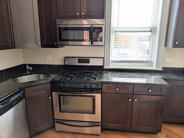 a kitchen with granite countertop cabinets stainless steel appliances and a window