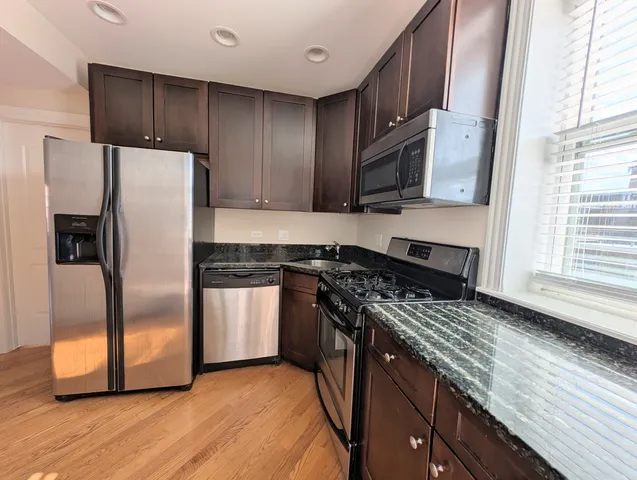 a kitchen with stainless steel appliances granite countertop a stove a refrigerator and a microwave
