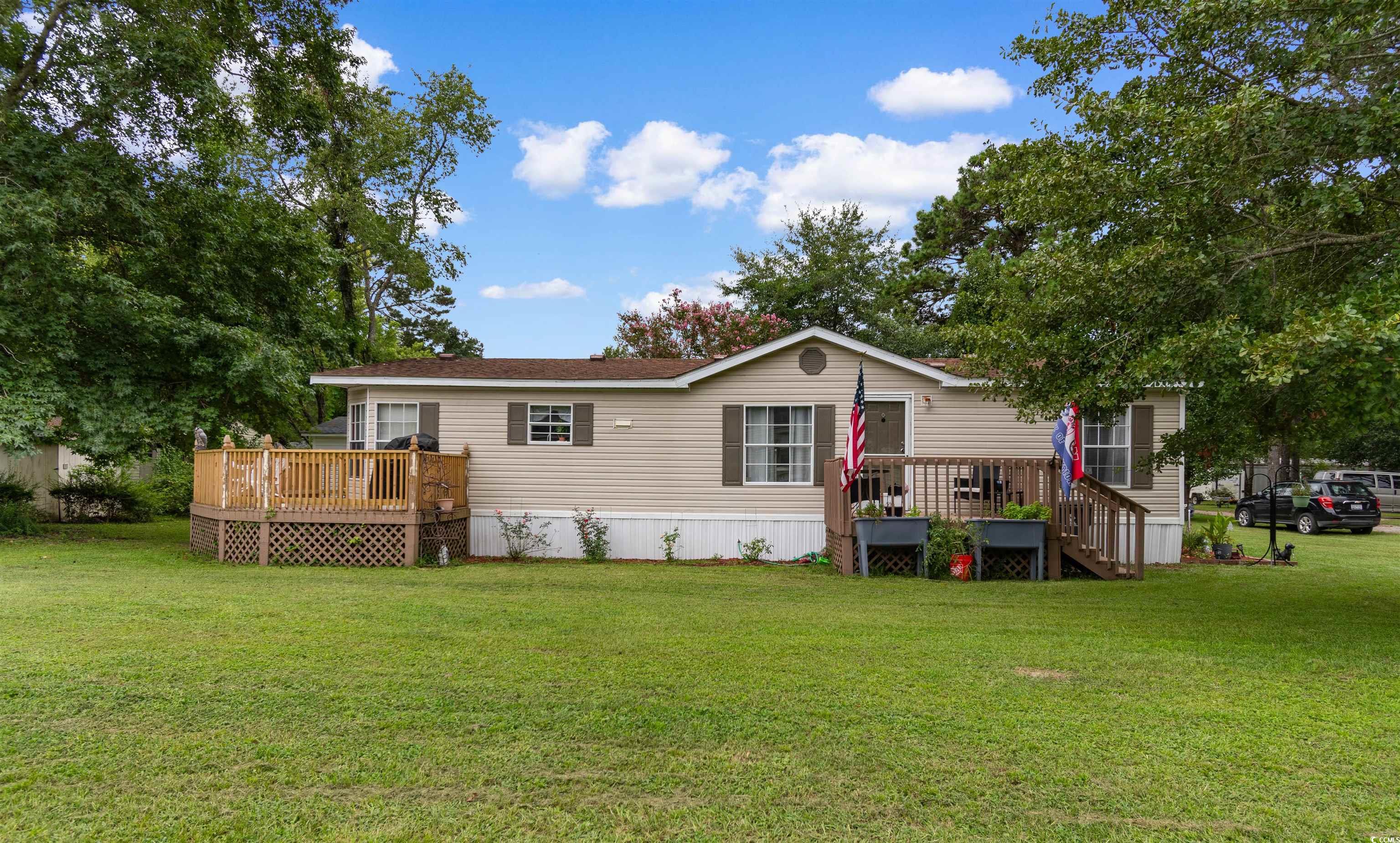 Back of house with a deck and a lawn