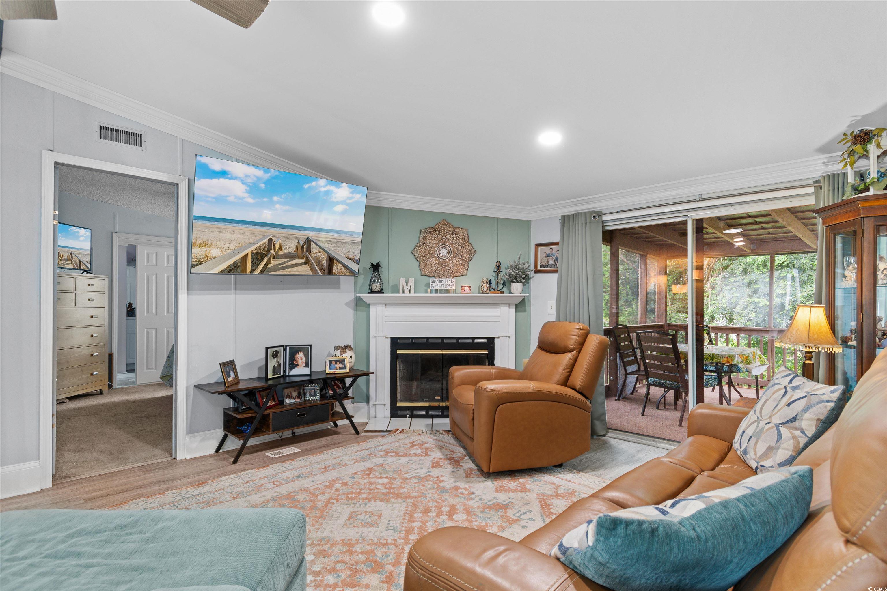 11140 Mcdowell Shortcut Road Murrells Inlet, SC 29576 - Photo 11 of 33 Living room featuring crown molding, a glass covered fireplace, wood finished floors, and recessed lighting